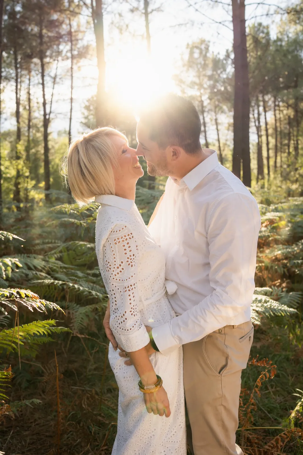 Couple s'enlaçant en forêt à contre-jour